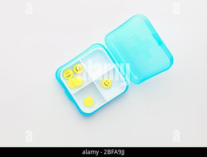 Box and pills with drawn faces on white background Stock Photo
