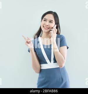 Portrait of young happy asian businesswoman using smart mobile phone isolated over white background in work place. Stock Photo