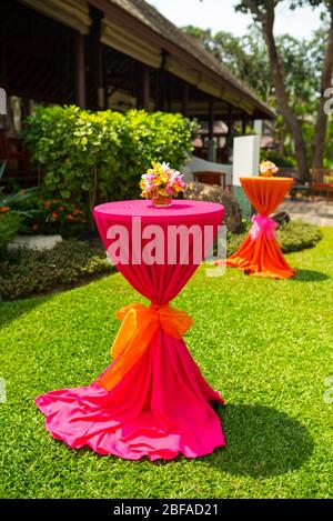colorful beautiful orchid bouquet decor in glass vase setup on the wooden dinner table in India wedding venue reception. Stock Photo