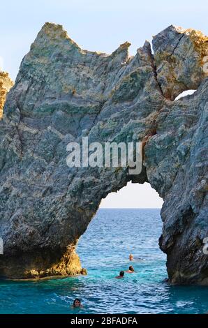 Skiathos, Greece - October 3rd 2012: unidentified people swimming through the rockhole named Tripia Petra on Lalaria beach, this beach is reachable on Stock Photo