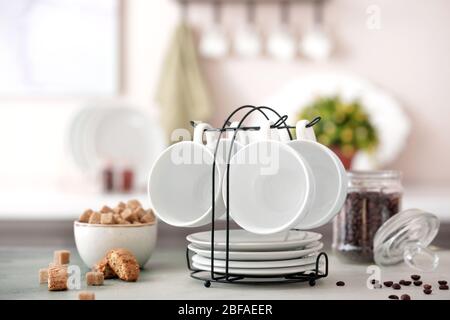 Holder with cups and saucers on kitchen table Stock Photo