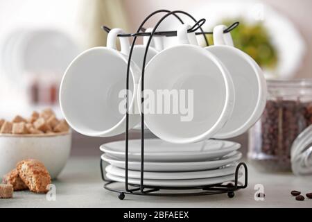 Holder with cups and saucers on kitchen table Stock Photo