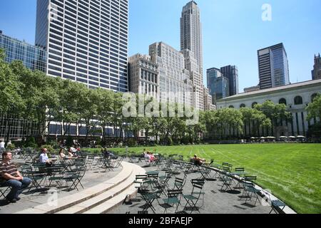 People relaxing on a beautiful spring summer day at Bryant Park, in Midtown Manhattan at 42nd Street between 5th and 6th Avenue in New York City, USA Stock Photo