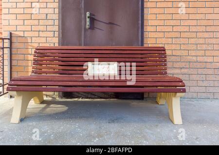 A wooden bench sitting in front of the door on a brick building. Stock Photo