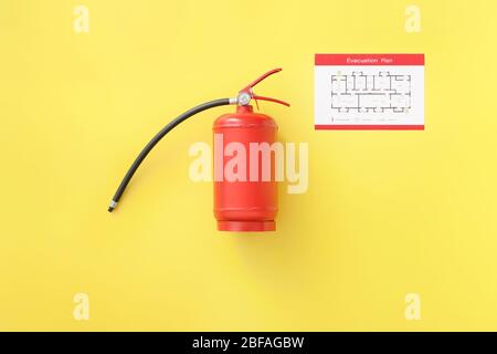 Fire extinguisher and evacuation plan on color background Stock Photo