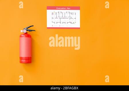 Fire extinguisher and evacuation plan on color background Stock Photo
