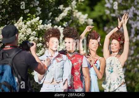 MOSCOW, RUSSIA - 19 MAY, 2019 Fashionable hipster girls and a guy posing for a photographer in blooming lilacs. Stock Photo