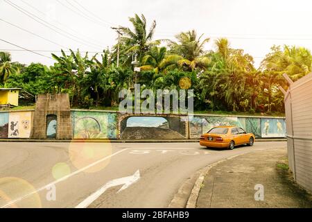 Caribbean, Trinidad and Tobago - February 05, 2018: city road with yellow car and streetscape graffiti Stock Photo