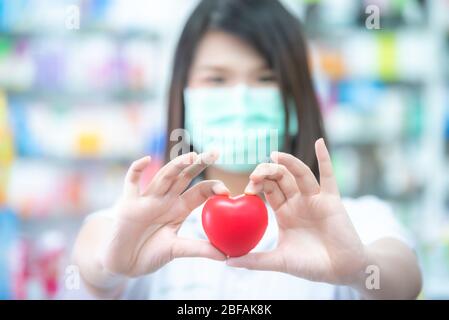 Asian women medical doctor holding a red heart ball with blurred background. Concept of health care. Stock Photo