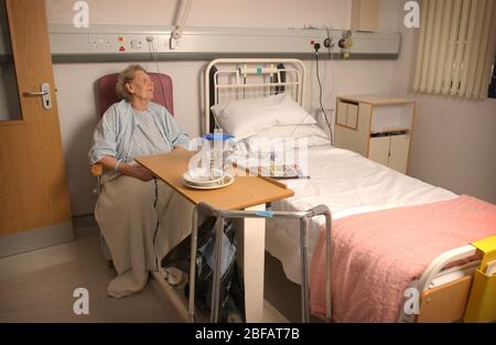 An Elderly Lady by her bed in a Hospital Ward Stock Photo