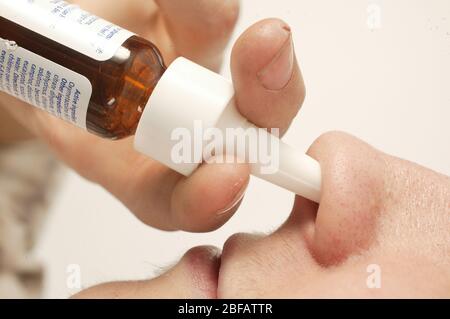 Young man using a nasal spray. Nasal spray are ideal for the relief of nasal congestion. Nasal congestion occurs when the membrane that lines the nose Stock Photo