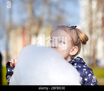 Cute little girl eating cotton candy. Happy childhood and children's emotions Stock Photo