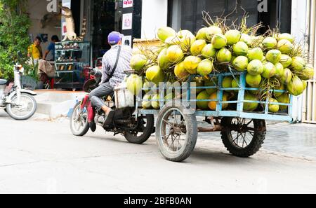 Phnom Penh, Cambodia - June 25,2018: Unidentified Coconut seller on bicycle waiting for costumer. Street life scene of an cambodian city. Stock Photo