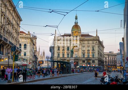 Milan, Italy, September 8, 2018: Piazza Cordusio square with Generali building and view of Duomo di Milano cathedral in historical city centre at suns