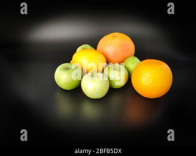 Whole fruits green apples, orange, grapefruit and lemon on black background. Concept - vegetarian and healthy food to improve the immunity Stock photo Stock Photo