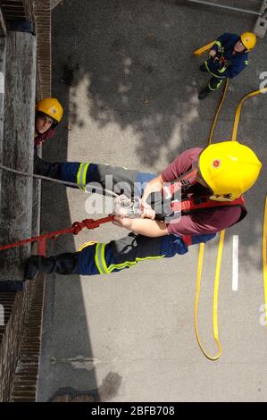 A firefighter climbing rope up side building on training exercise ...