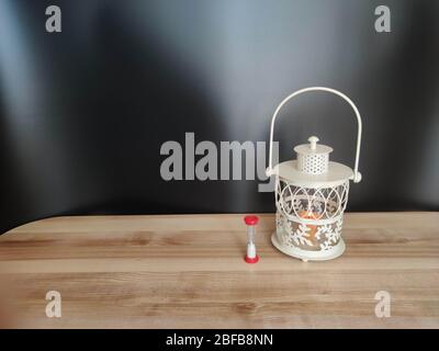 Vintage lantern with an orange candle and sand clock on the table with black backdrop. Concept - Ramadan kareem holiday celebration. Stock Photo