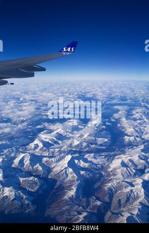 CANADA - NOV 24th, 2018: A view of a vast landscape of mountains covered in snow taken from the window of an airplane showing the wing Stock Photo