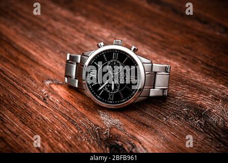 Metal luxury wrist watch on a brown wooden table Stock Photo
