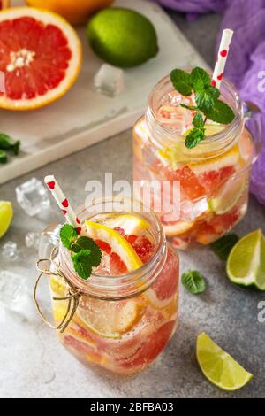 Ice refreshing drink. Mason jar mug filled with Fresh mojito cocktail with grapefruit, lime and mint on a background of gray stone. Stock Photo