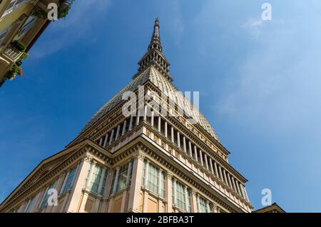 Mole Antonelliana tower building with spire steeple is major landmark and symbol of Turin Torino city, view from below, blue sky background, Piedmont, Stock Photo