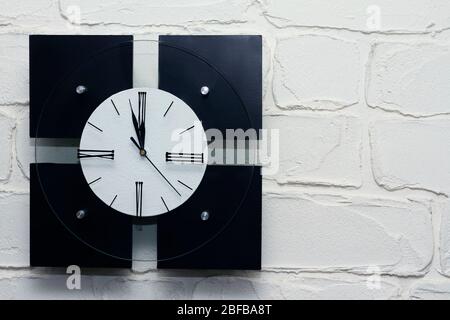 Square black and white clock on a white brick wall, background or concept Stock Photo