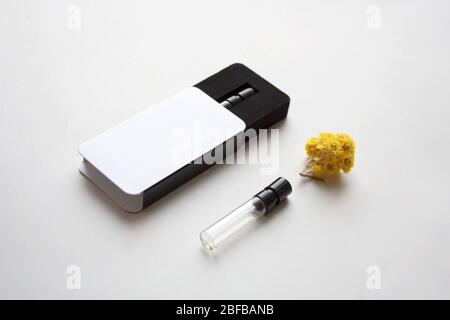 Blank branding mockup of glass perfume bottle sample with package box and small yellow flower on white background Stock Photo