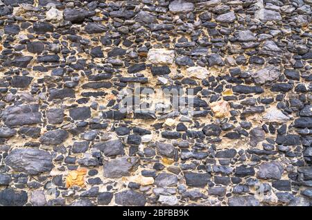 Black stone old ancient wall background with copy space. Abstract old close-up texture. Patterned view. Stock Photo