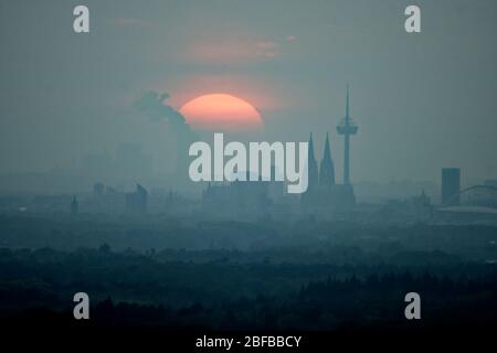 Cologne, Germany. 17th Apr, 2020. The sun sets behind the skyline of Cologne. In the background you can see the lignite power plant Niederaussem. Credit: Henning Kaiser/dpa/Alamy Live News Stock Photo
