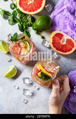 Summer ice refreshing drink. Fresh mojito cocktail with grapefruit, lime and mint in a glass on a gray stone background. Stock Photo