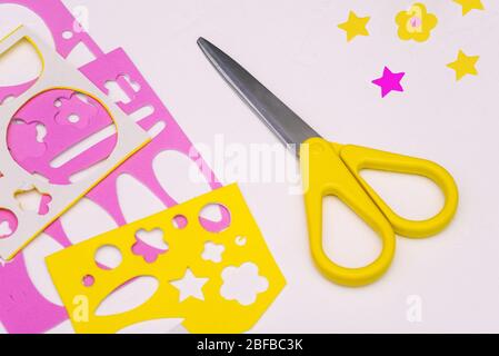 Scissors and paper with figures on a white table. Cutting out of colored paper. The development of fine motor skills in children Stock Photo