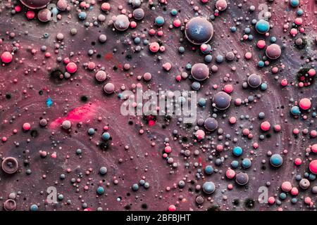 Color drops floating in oil and water over a colorful underground with oil painting effect. Stock Photo