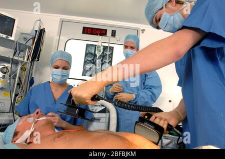 Doctors using a defibrillator to resuscitate a male heart attack victim Stock Photo