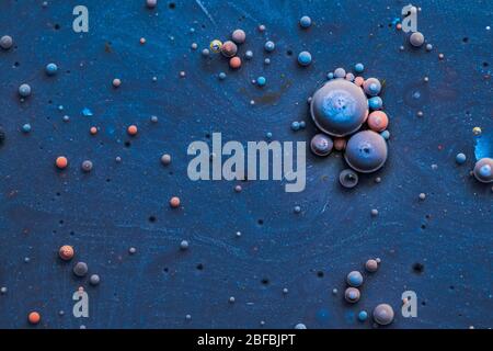 Color drops floating in oil and water over a colorful underground with oil painting effect. Stock Photo
