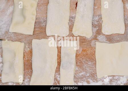 Uncooked dough on a wooden board. Sliced pieces of text for making buns. Confectionery Stock Photo