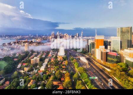 North Sydney and City CBD across the harbour covered by thick fog on a sunny morning - elevated aerial view. Stock Photo