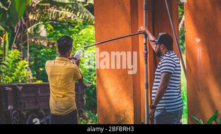 Meerigama, Sri Lanka - November 9th, 2019: Two young thirsty man filling plastic bottle with water available at the station during hot sunny day Stock Photo