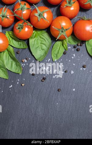 Cherry tomatoes and basil leaves on black background Stock Photo