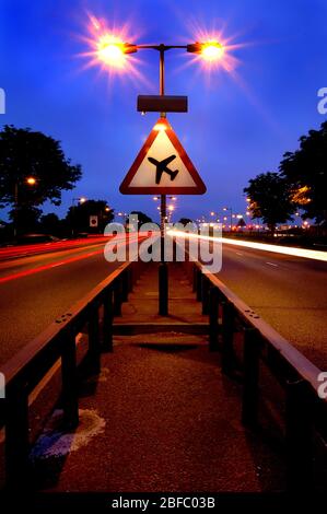 A long exposure of a dual carriageway close to Heathrow Airport and a road sign warning  of low flying aircraft. Stock Photo