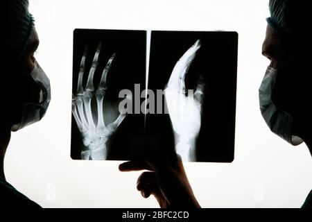 Two surgeons examine an x-ray of a hand before surgery Stock Photo