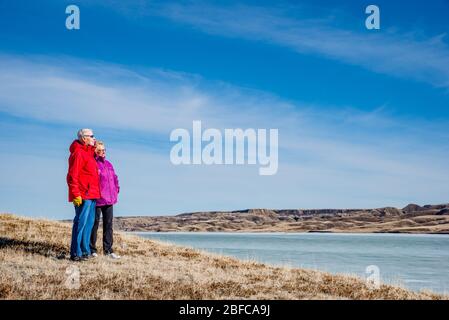 Senior couple standing overlooking an ice-covered Lake Diefenbaker Stock Photo
