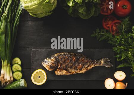 Sea bream cooked and ready to eat.Green vegetables around the fish Mediterranean cuisine. Top view Stock Photo
