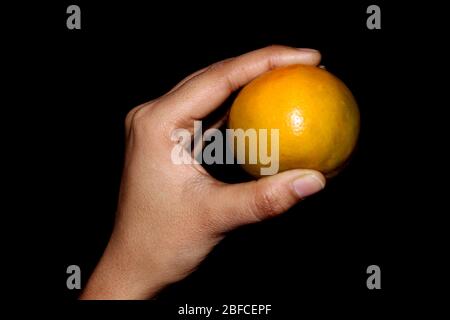 hand holding fresh sliced orange fruit isolated on black background Stock Photo