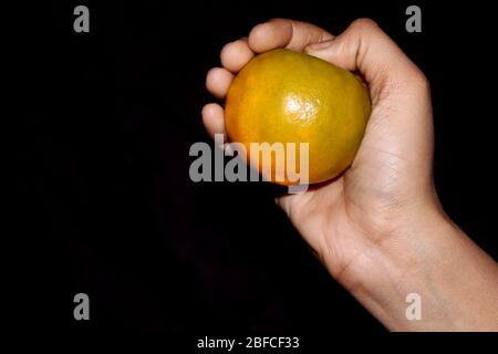 hand holding fresh sliced orange fruit isolated on black background Stock Photo
