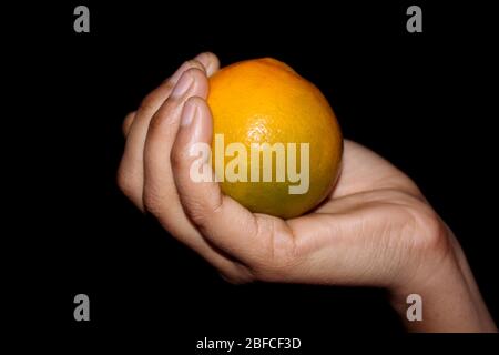 hand holding fresh sliced orange fruit isolated on black background Stock Photo