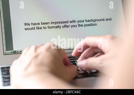Woman typing letter of offer on her computer. Employment or job offer concept. Stock Photo