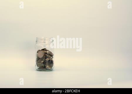 Metal coins, Russian rubles, lie in a transparent glass jar on a light background. Place for text and design. Stock Photo