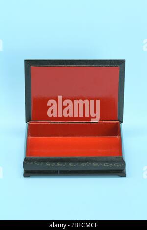 Black with gold painted empty lacquered wooden casket stands open. Inside is red. Stock Photo