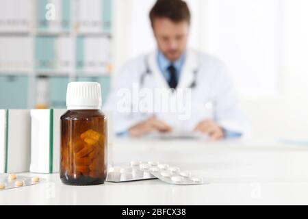 pills, blister, bottle and tablets boxes medicine on medical desk office with doctor on background Stock Photo