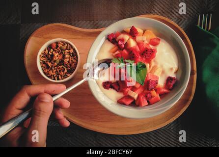 Full vegan breakfast of tropical fruit smoothie bowl with muesli as a way to stay healthy and cope during home quarantine due to the covid-19 pandemic Stock Photo
